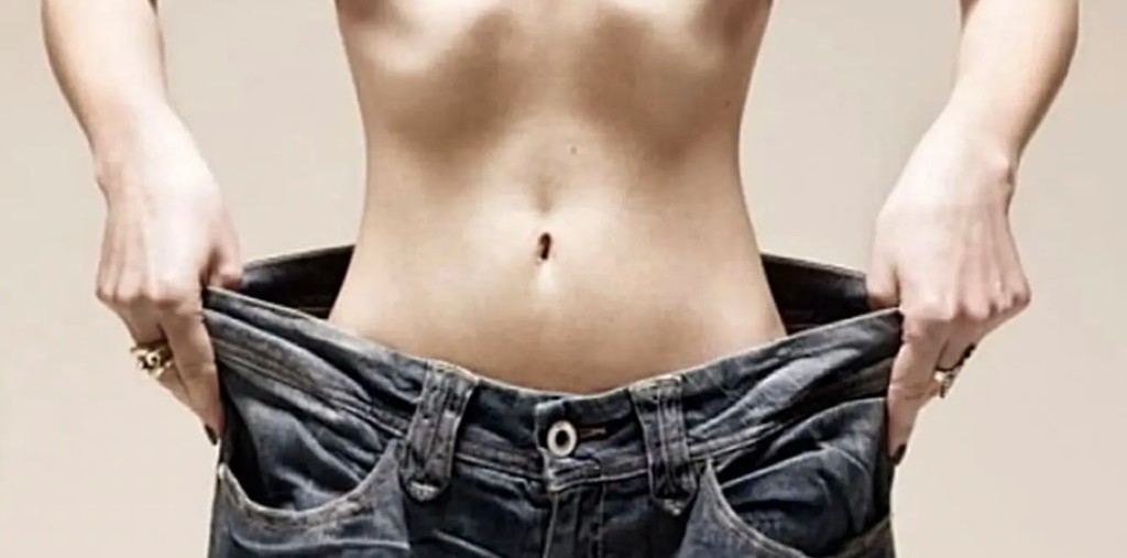 Person holding loose jeans — a lifestyle confidence moment after building consistent wellness habits